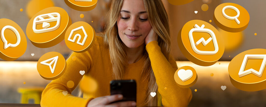 Smiling woman in a yellow sweater using her smartphone, surrounded by floating golden social media icons representing likes, messages, and engagement.